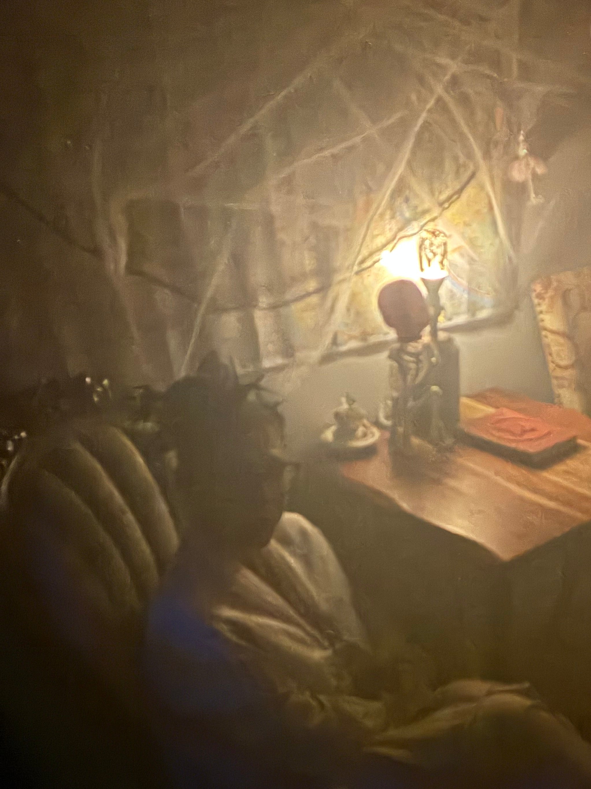 person sitting in spooky cobwebbed room with skeleton animal and doll head